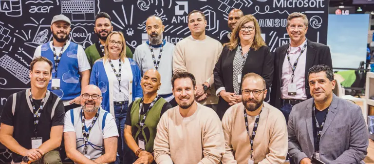 Un groupe de personnes posant pour une photo lors d'un événement technologique avec des logos en arrière-plan.