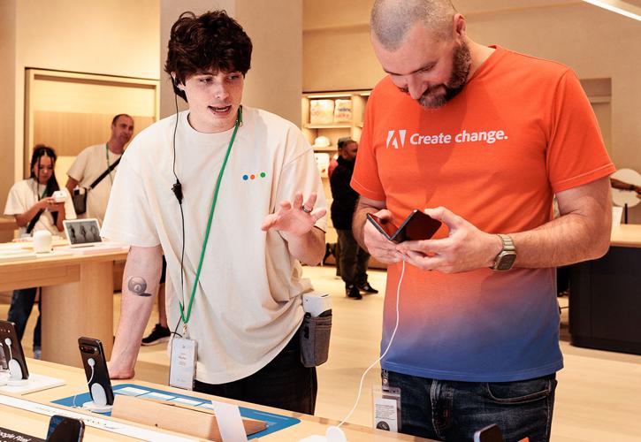 Un employé de magasin aide un client avec un téléphone dans un magasin de technologie.