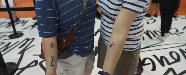 Deux personnes côte à côte montrent des tatouages d'étoiles assortis sur leurs bras.