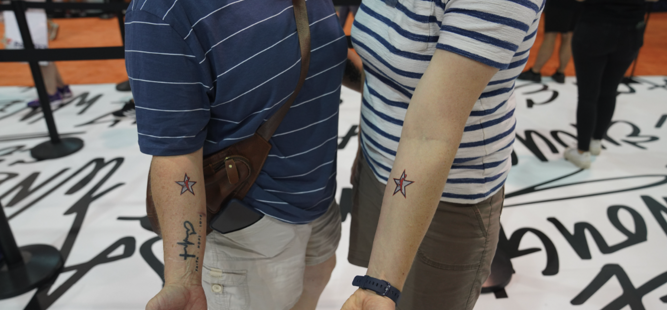 Deux personnes côte à côte montrent des tatouages d'étoiles assortis sur leurs bras.