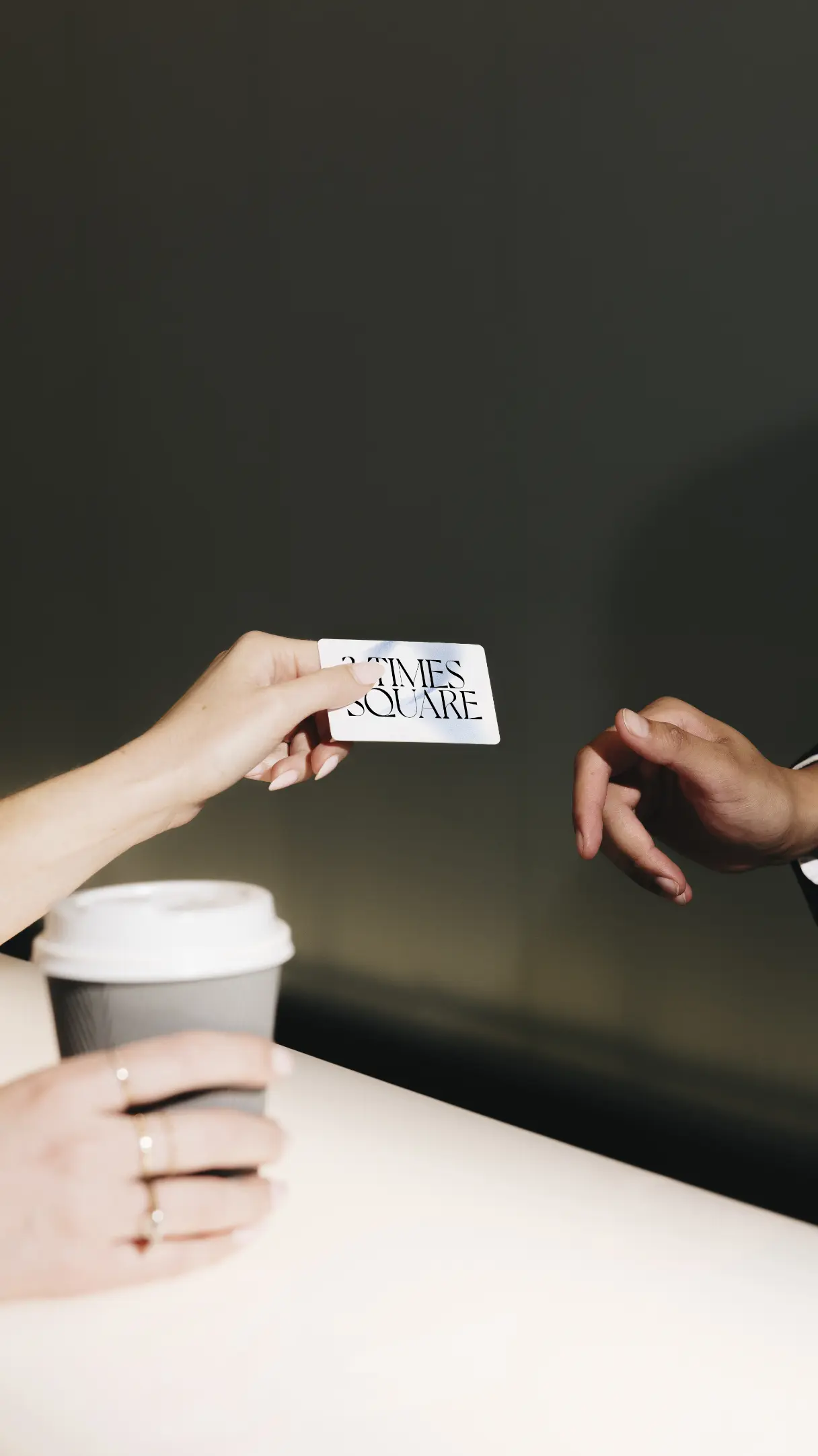 Une personne tend une carte étiquetée « TIMES SQUARE » à une autre personne au-dessus d'une table avec une tasse de café.