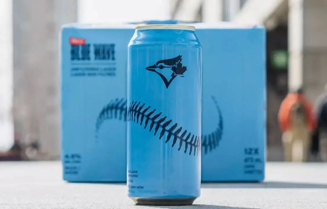 Une canette de bière bleue et blanche avec un design de couture de baseball et un logo d'oiseau.