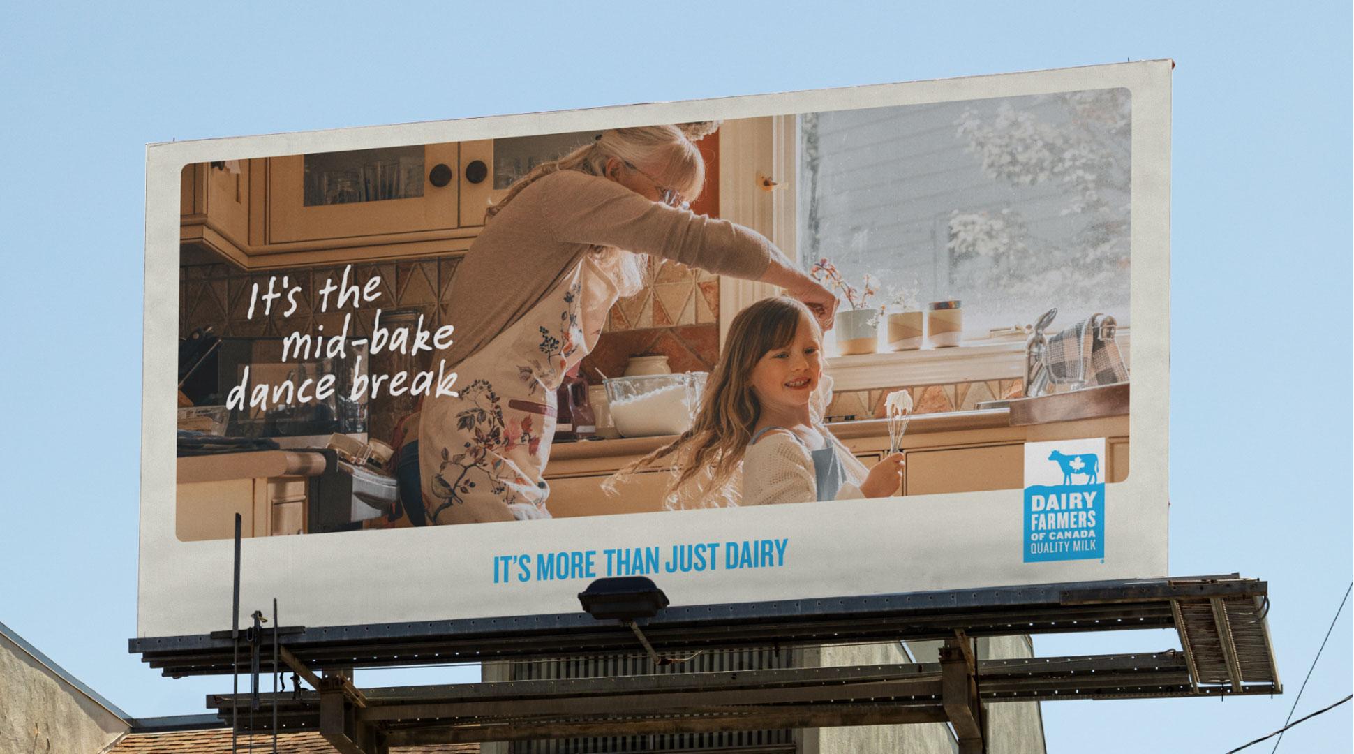 Un panneau d'affichage montre un enfant et une femme plus âgée dansant dans une cuisine, avec le texte "C'est la pause danse en pleine cuisson" et un logo des Producteurs laitiers du Canada.