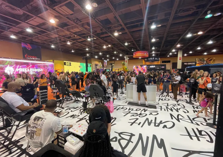Un salon ou une exposition animé avec des personnes rassemblées autour de divers stands et présentoirs.