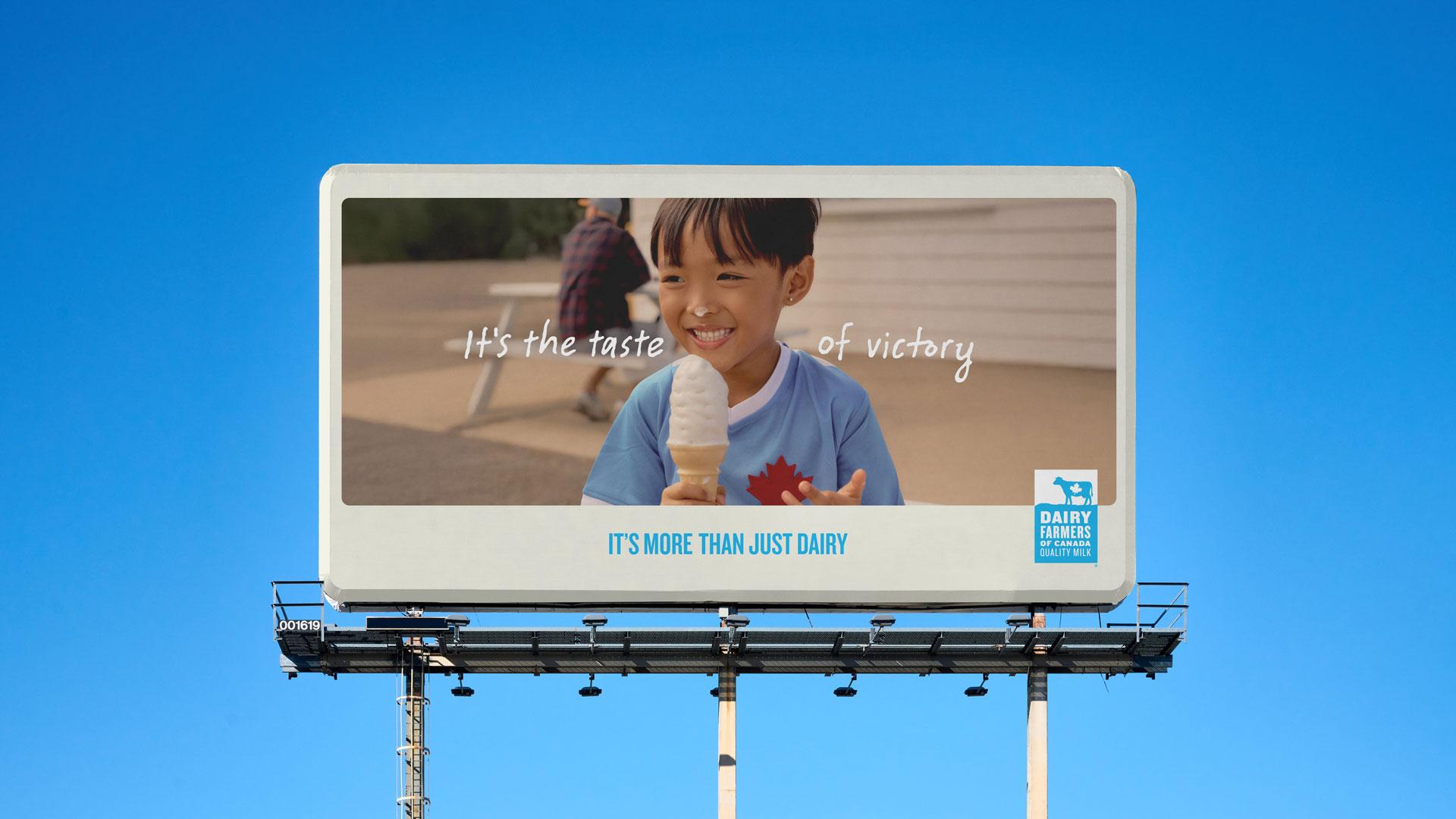 Un enfant souriant tient un cornet de crème glacée sur un panneau d'affichage qui dit "C'est le goût de la victoire", faisant la promotion des Producteurs laitiers du Canada.
