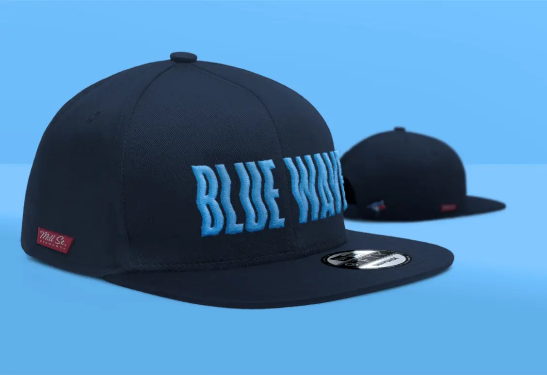 Two navy blue baseball caps with "BLUE WAVE" in blue letters, one facing forward and the other backward, on a blue background.