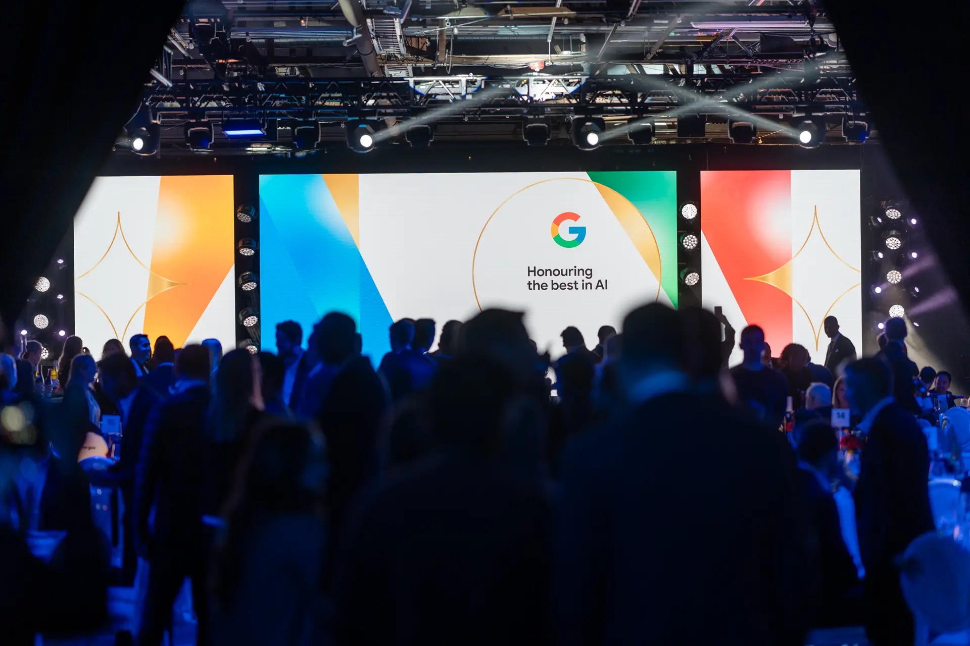Une grande audience rassemblée lors d'un événement sur le thème « Honorer le meilleur de l'IA », affiché sur un écran de scène illuminé.