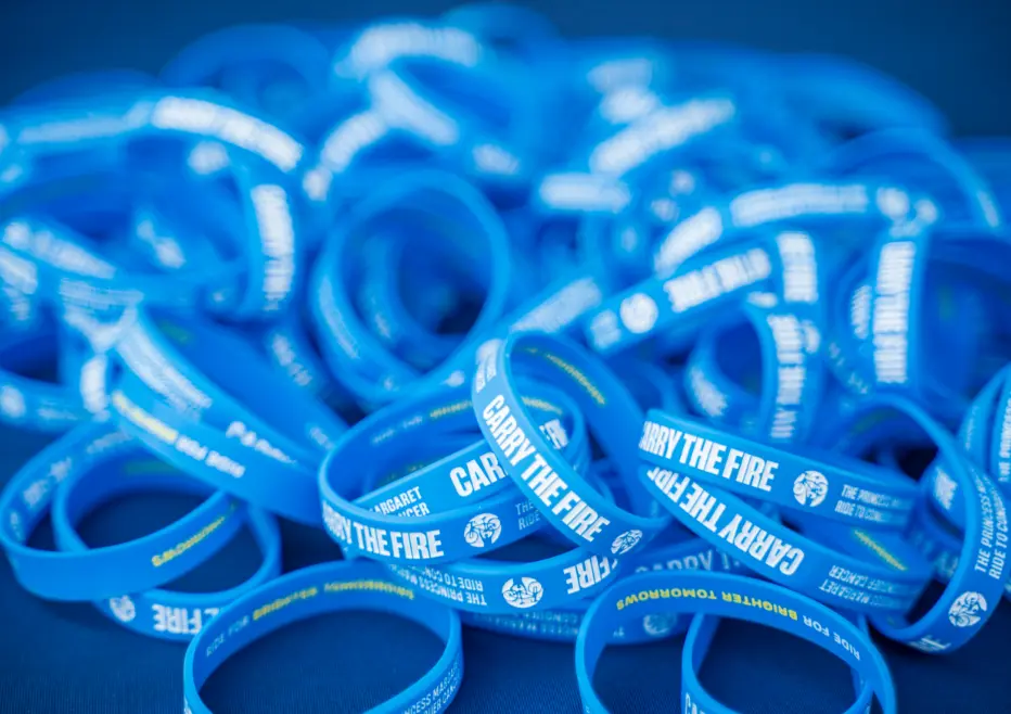 A pile of blue wristbands with "CARRY THE FIRE" printed on them.