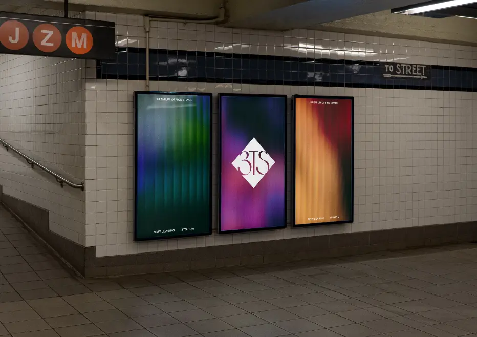 Trois affiches numériques colorées sur un mur de station de métro avec un logo en losange blanc au centre.