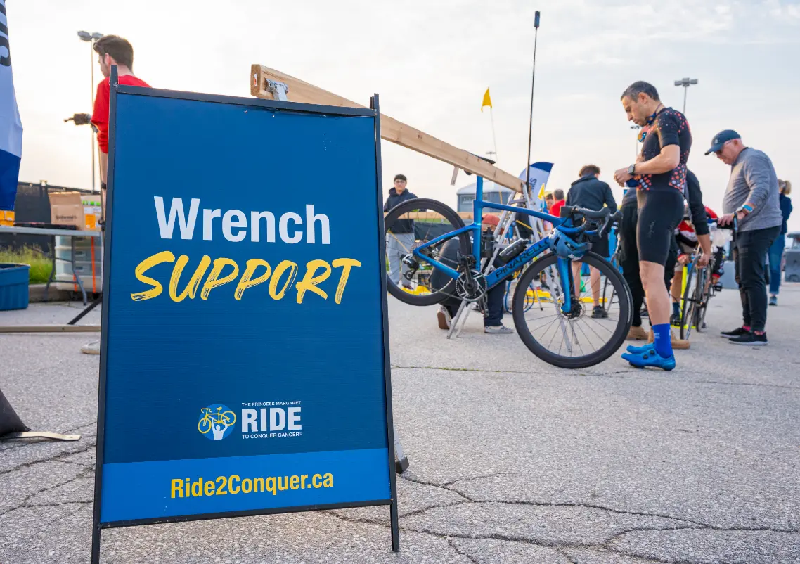A bike repair station with a "Wrench Support" sign and people working on bicycles.