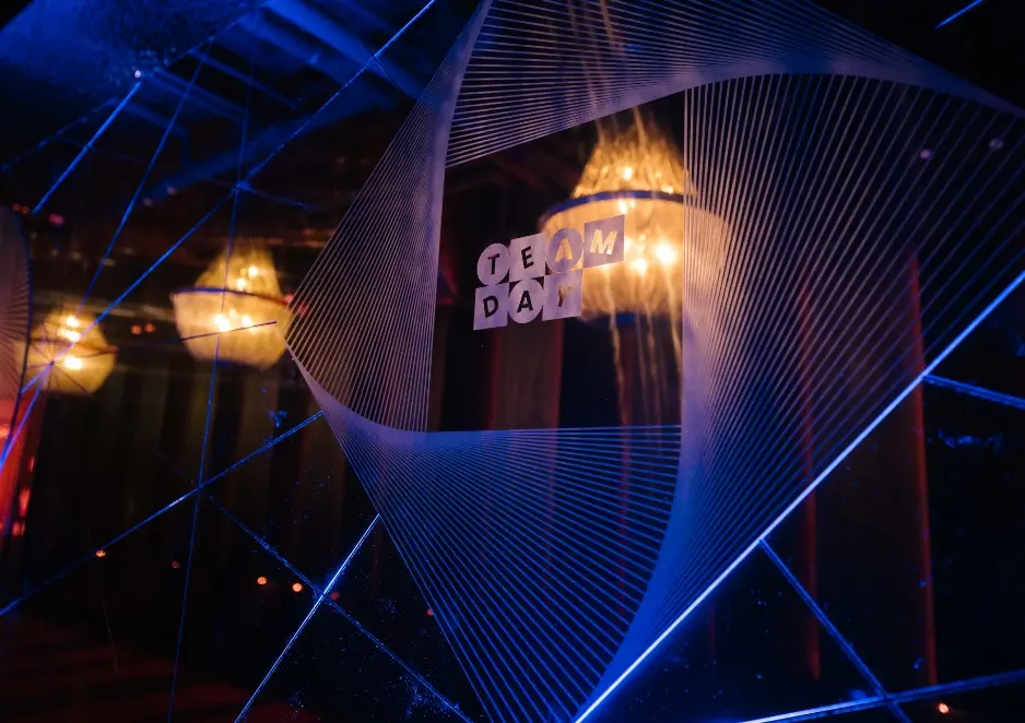 A geometric design with the words "Team Day" reflected on a glass surface under dim lighting.