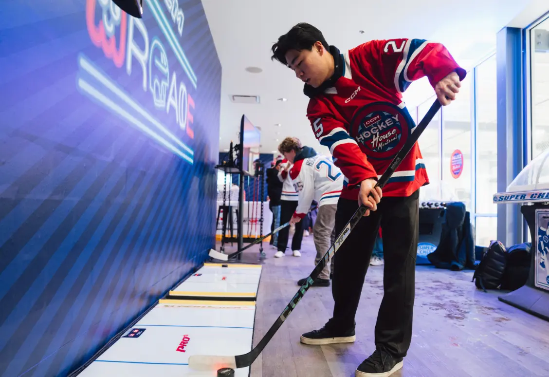 Une personne en maillot de hockey s'entraîne aux compétences de hockey intérieur avec d'autres personnes en arrière-plan.