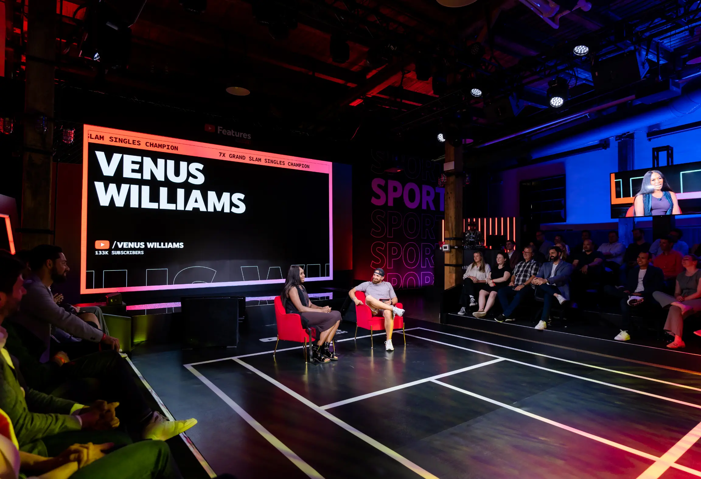 Une personne est interviewée sur scène avec un public qui regarde, et un grand écran affiche « Venus Williams » ainsi que des informations sur les abonnés.