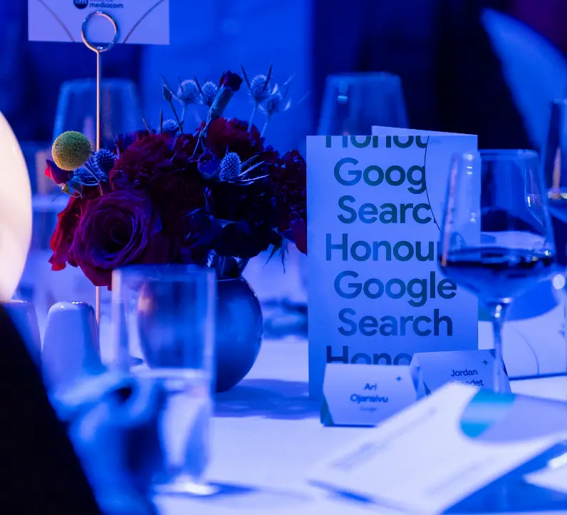 Couvert de table avec des fleurs, de la verrerie et un programme qui dit « Google Search Honour ».